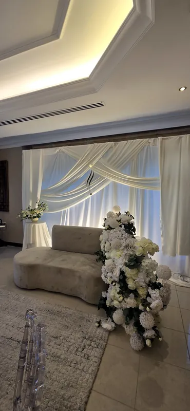 Sofa incurvé avec des fleurs blanches devant des drapés blancs