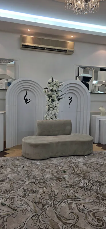 Panneaux blancs en arche avec un sofa et des fleurs sur un tapis à motifs