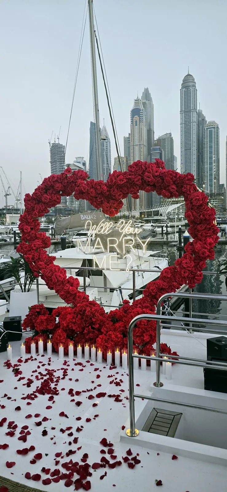 Сердце из красных роз с надписью Will you marry me на палубе яхты, позади башни