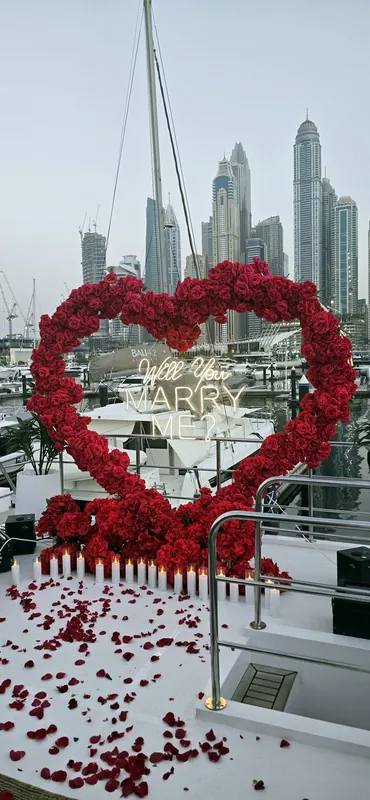 Сердце из красных роз с надписью Will you marry me на палубе яхты, позади башни