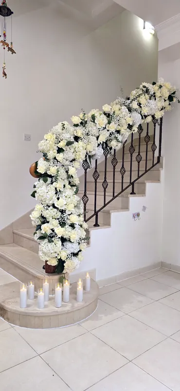 Rampe d’escalier habillée de fleurs blanches avec des bougies sur les marches