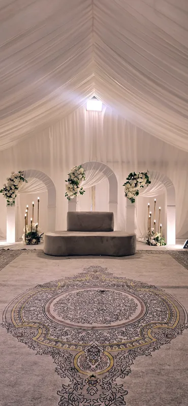 Plafond drapé de blanc au-dessus d’arches, d’un sofa et d’un tapis à motifs